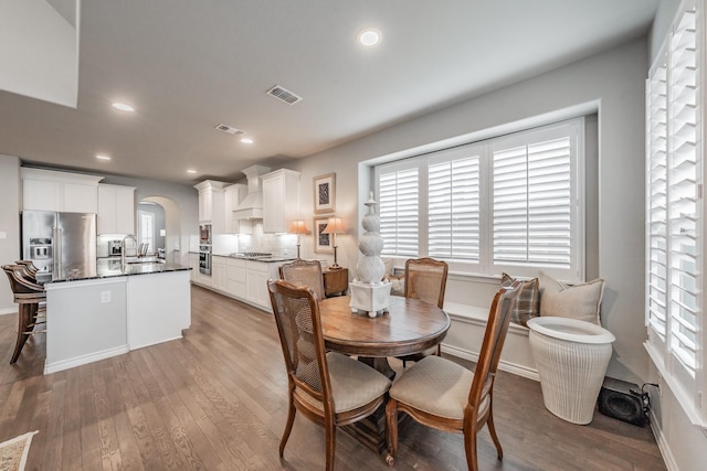 dining room featuring visible vents, arched walkways, wood finished floors, and recessed lighting