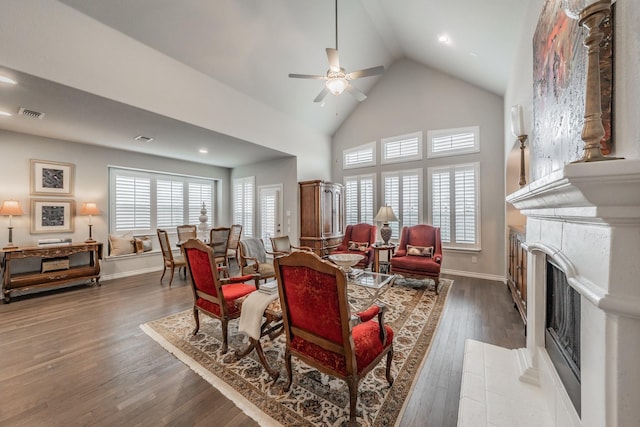 living room with baseboards, ceiling fan, wood finished floors, a fireplace, and high vaulted ceiling