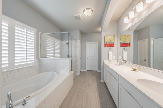 full bathroom with double vanity, a sink, a shower stall, and a bath