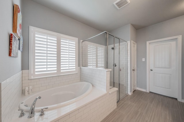 bathroom featuring a stall shower, visible vents, and a garden tub