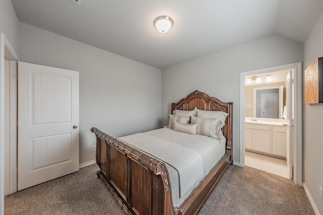 bedroom featuring carpet floors, ensuite bath, baseboards, and lofted ceiling