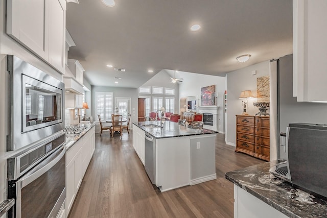 kitchen with dark wood-style flooring, a fireplace, stainless steel appliances, white cabinets, and a sink