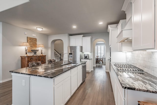 kitchen featuring decorative backsplash, appliances with stainless steel finishes, dark wood-type flooring, white cabinets, and a sink