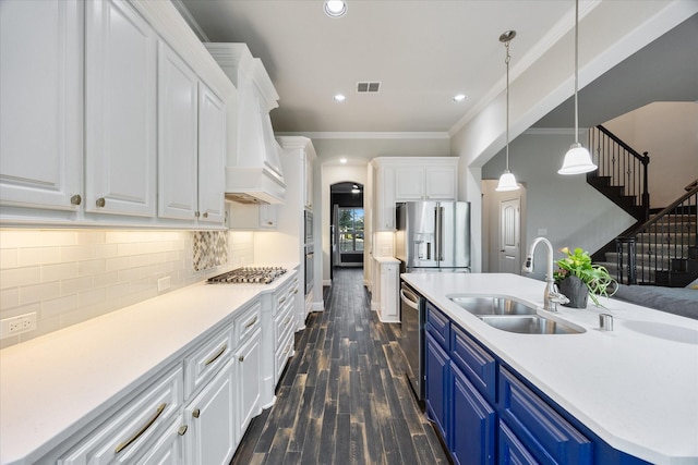 kitchen featuring white cabinets, appliances with stainless steel finishes, blue cabinets, premium range hood, and a sink