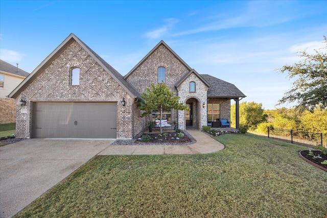 french country style house featuring brick siding, fence, a garage, driveway, and a front lawn