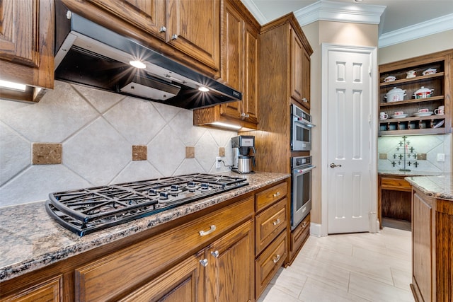 kitchen featuring light stone counters, brown cabinets, under cabinet range hood, and black gas stovetop