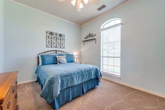 carpeted bedroom featuring baseboards, a ceiling fan, visible vents, and crown molding