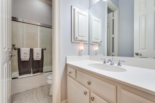 bathroom with bath / shower combo with glass door, a textured wall, toilet, marble finish floor, and vanity