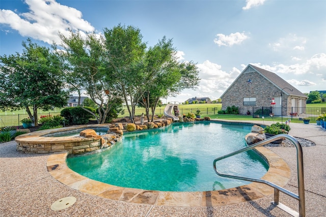 view of pool with a yard, a pool with connected hot tub, a water slide, and fence