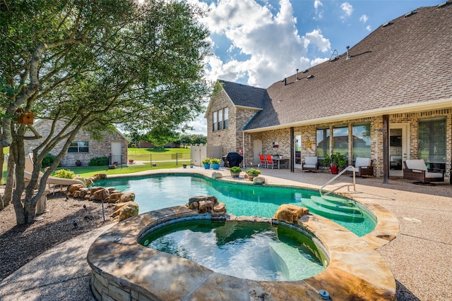 view of pool with a patio, fence, and a pool with connected hot tub