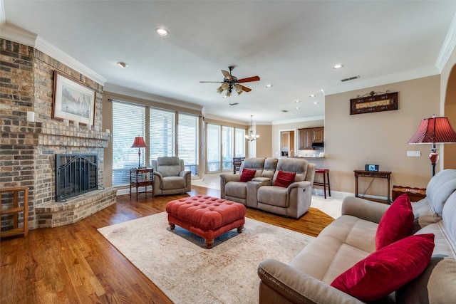 living area featuring light wood finished floors, visible vents, a fireplace, and ornamental molding