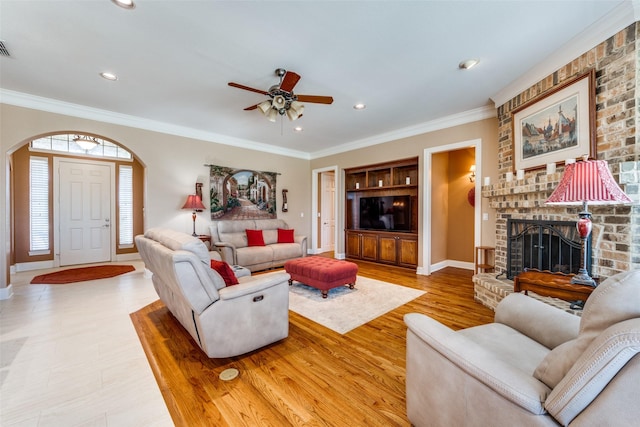 living area featuring baseboards, ornamental molding, wood finished floors, a fireplace, and recessed lighting