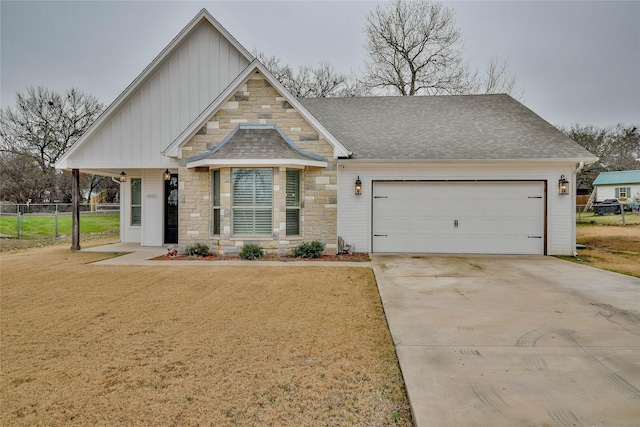 craftsman-style house featuring driveway, a garage, stone siding, fence, and board and batten siding