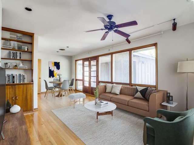 living room with french doors, light wood finished floors, and ceiling fan