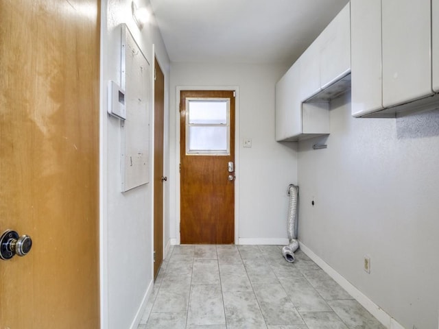 laundry room featuring electric dryer hookup, light tile patterned flooring, cabinet space, and baseboards