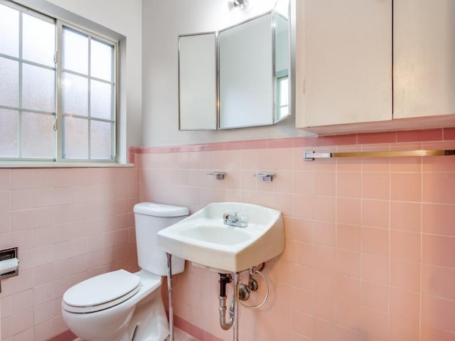 bathroom featuring toilet, a wainscoted wall, and tile walls