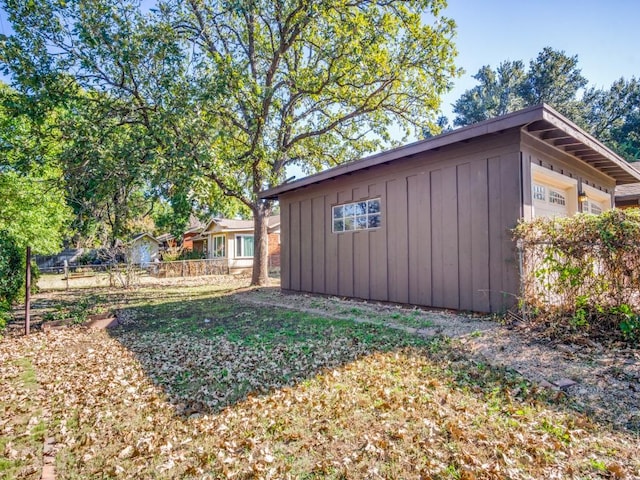 view of outdoor structure featuring an attached garage and fence