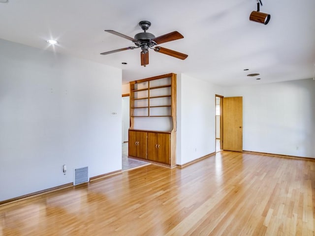 spare room featuring a ceiling fan, light wood-type flooring, visible vents, and baseboards