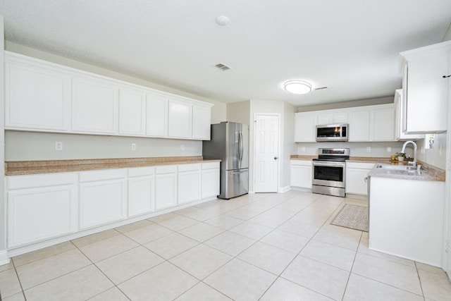 kitchen featuring stainless steel appliances, light countertops, visible vents, white cabinetry, and a sink