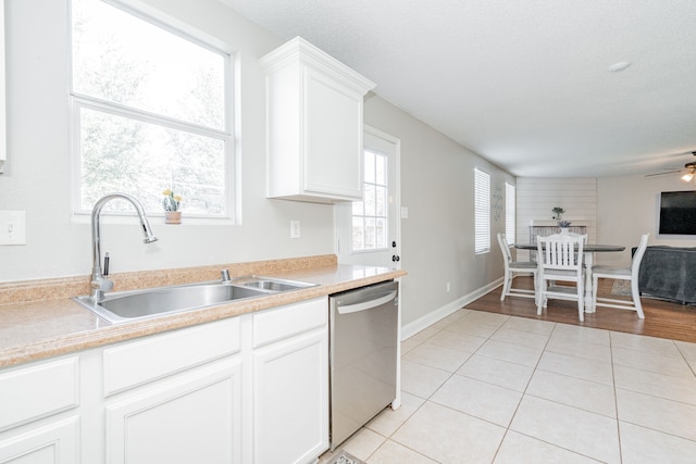 kitchen with light countertops, stainless steel dishwasher, white cabinets, light tile patterned flooring, and a sink