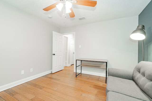 sitting room featuring visible vents, light wood-style floors, ceiling fan, a textured ceiling, and baseboards