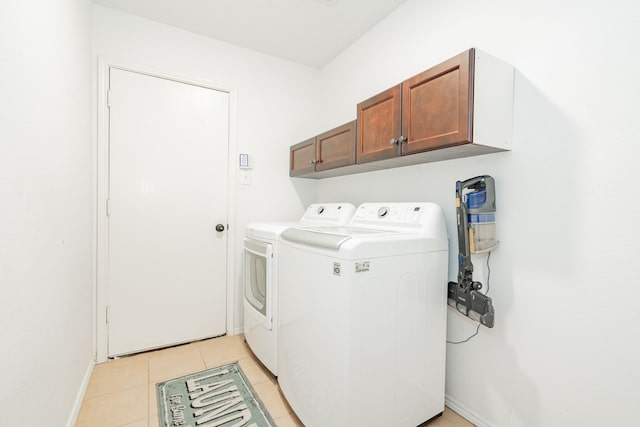 washroom with baseboards, cabinet space, washing machine and clothes dryer, and light tile patterned floors