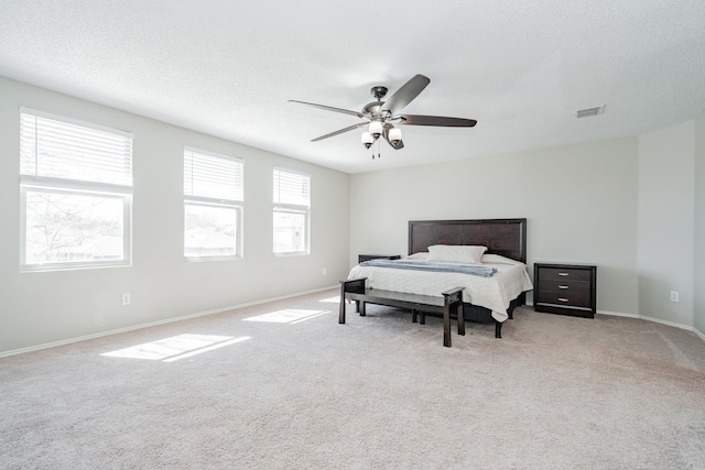 bedroom with light carpet, a textured ceiling, and baseboards