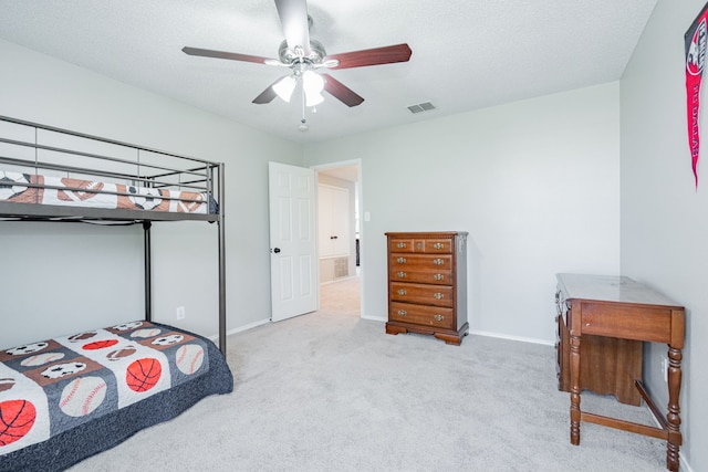 carpeted bedroom featuring ceiling fan, a textured ceiling, visible vents, and baseboards