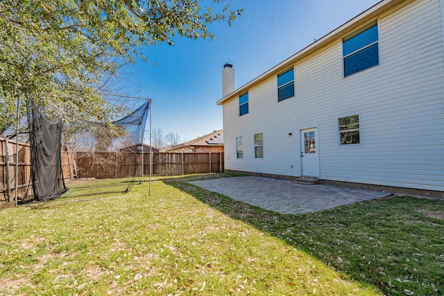 back of house featuring a yard, a patio, a chimney, and fence