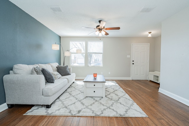 living room featuring baseboards, visible vents, and wood finished floors