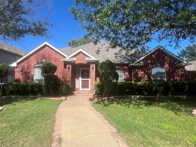 view of front facade featuring brick siding, roof with shingles, and a front yard