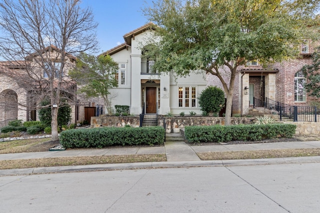 view of front of home with a tiled roof, fence, and stucco siding