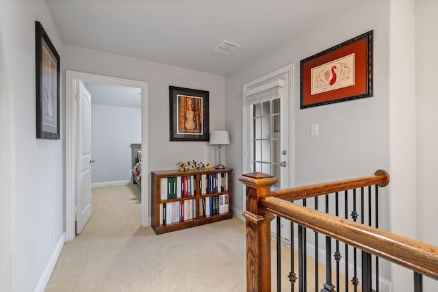 corridor with visible vents, light carpet, an upstairs landing, and baseboards