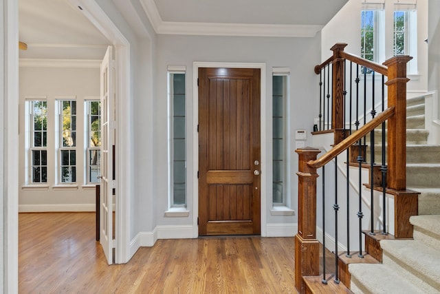 foyer entrance featuring stairs, crown molding, baseboards, and wood finished floors