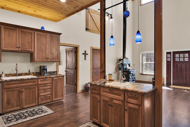 kitchen with wood ceiling, dark wood-style flooring, dark stone counters, and a sink