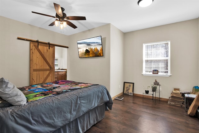 bedroom with wood finished floors, baseboards, and a barn door