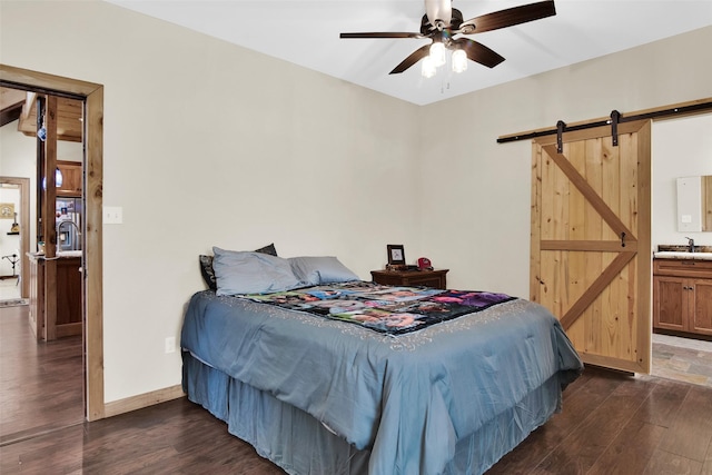 bedroom with baseboards, dark wood finished floors, a sink, and a barn door