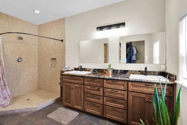 full bathroom featuring tiled shower, a sink, and double vanity