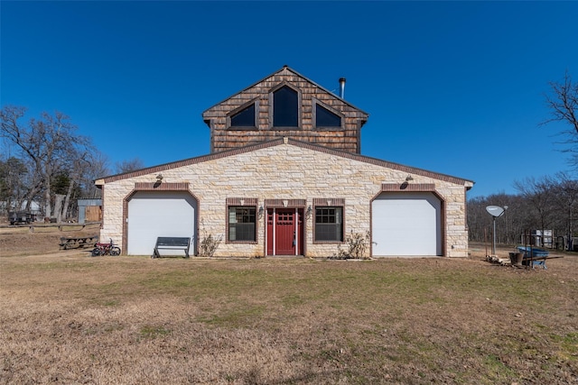 traditional-style home featuring a garage, a front yard, and stone siding
