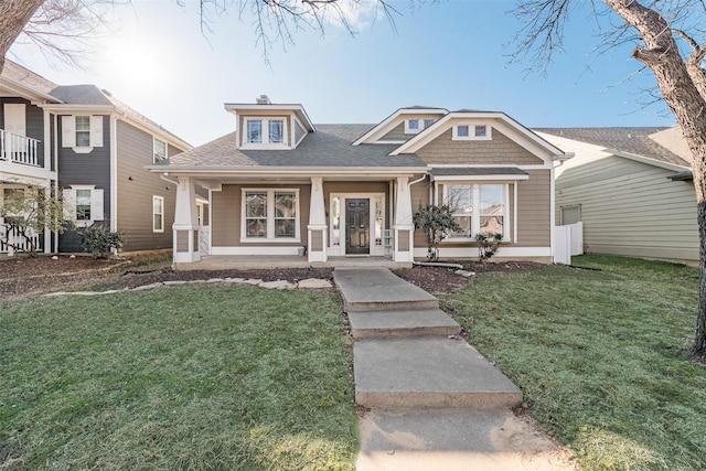 view of front of property featuring a porch, a front yard, and roof with shingles