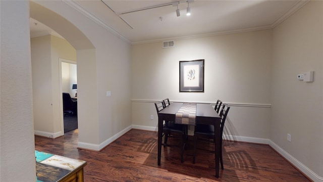dining room featuring baseboards, visible vents, arched walkways, wood finished floors, and crown molding