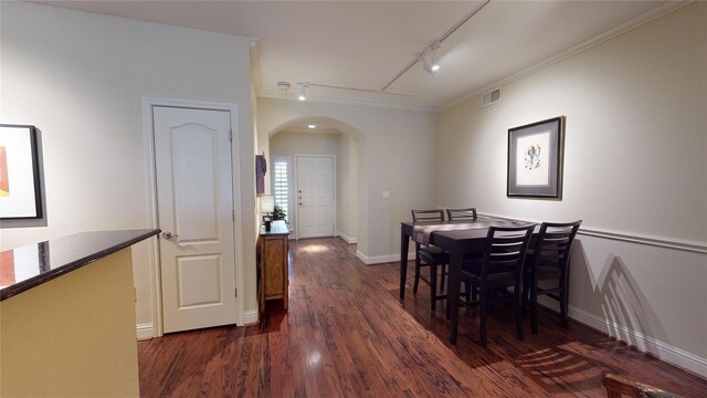 dining space with arched walkways, dark wood-style flooring, visible vents, baseboards, and track lighting