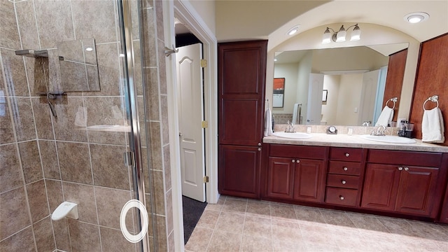 bathroom with double vanity, a stall shower, a sink, and tile patterned floors