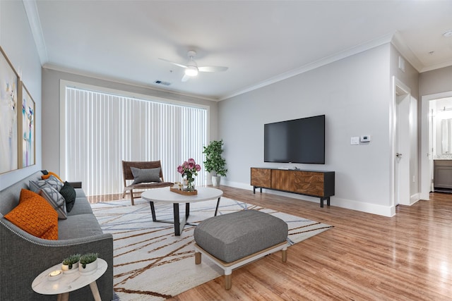 living area featuring light wood-style floors, baseboards, visible vents, and crown molding