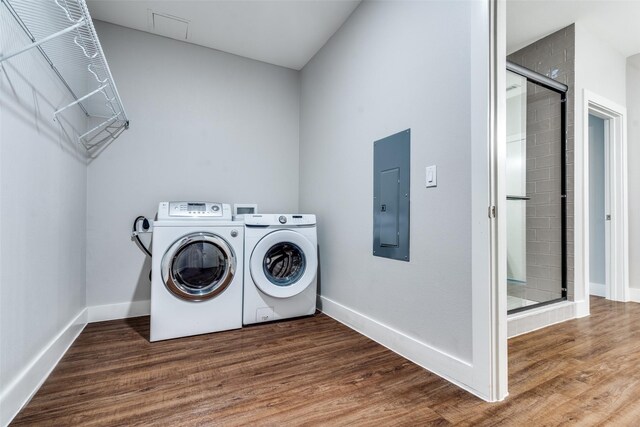 washroom with laundry area, wood finished floors, baseboards, electric panel, and washer and clothes dryer