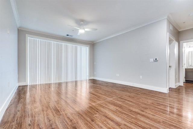 spare room with ornamental molding, wood finished floors, visible vents, and a ceiling fan