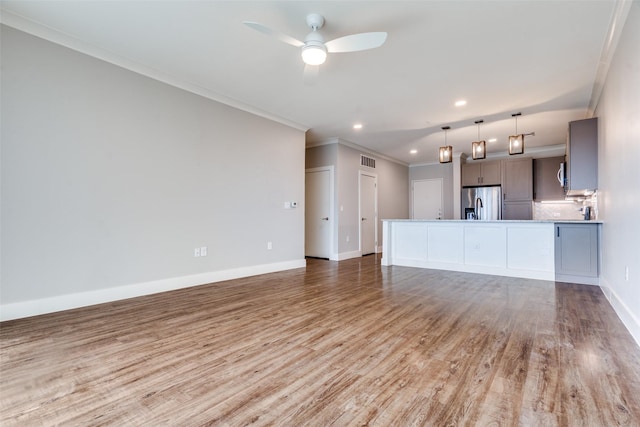 unfurnished living room with crown molding, light wood finished floors, visible vents, ceiling fan, and baseboards