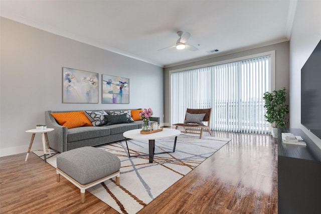 living room with baseboards, visible vents, ceiling fan, ornamental molding, and wood finished floors