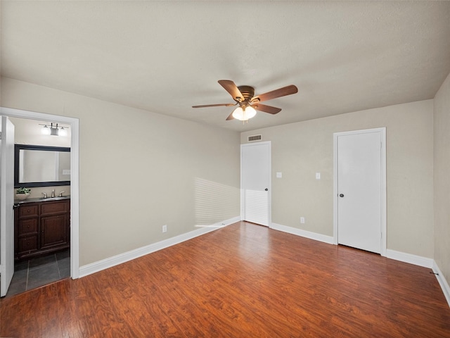 unfurnished bedroom featuring a sink, wood finished floors, visible vents, and baseboards