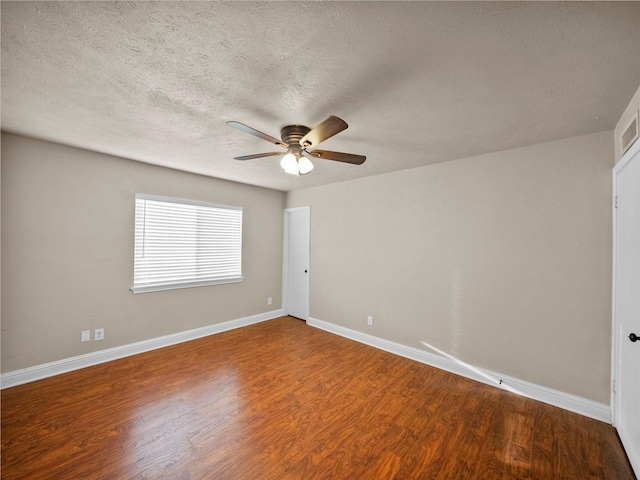 empty room featuring a textured ceiling, wood finished floors, and baseboards